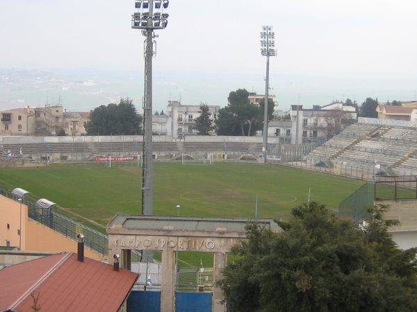 L'arco d'ingresso con la scritta «Campo sportivo» e, oltre il campo, gli spalti in cemento.